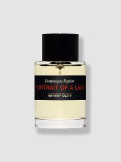 Flacone di profumo in vetro trasparente con la scritta "Dominique Ropion PORTRAIT OF A LADY", con tappo nero ed etichetta nera, contenente un liquido giallo chiaro, su uno sfondo grigio semplice.