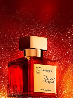 Un flacone del profumo Maison Francis Kurkdjian Paris Baccarat Rouge 540 con un tappo dorato si erge davanti a uno sfondo rosso e oro brillante.