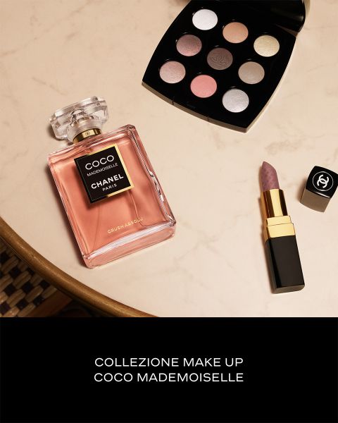Un flacone di profumo Chanel Coco Mademoiselle, una palette di ombretti e un rossetto giacciono su una superficie di marmo. Testo: Collezione Make Up Coco Mademoiselle.