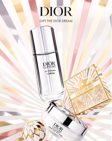 I prodotti per la cura della pelle Dior, tra cui un siero, una crema e una scatola decorativa dorata, sono presentati su uno sfondo radioso con raggi rosa chiaro, dorati e bianchi. Il testo recita: "DIOR. REGALA IL SOGNO DI DIOR.