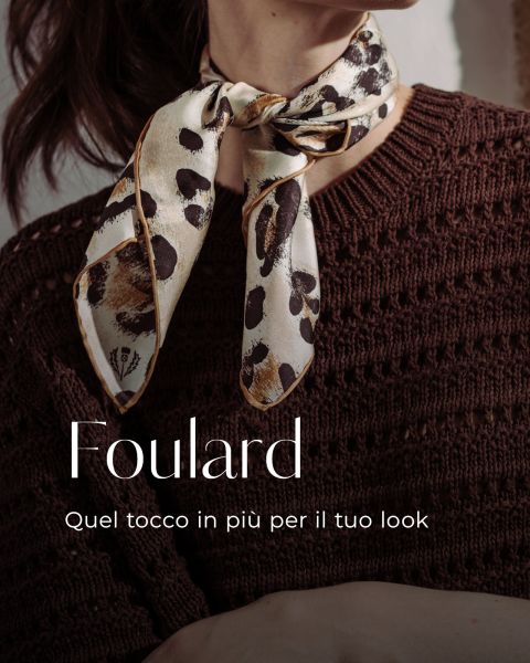 Una donna indossa un maglione di maglia marrone e un foulard di seta con stampa leopardata annodato al collo. Il testo recita: "Foulard. Quel tocco in più per il tuo look.