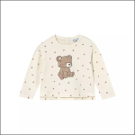 Ein cremefarbenes, langärmeliges Kinderhemd mit einem Muster aus kleinen braunen Quadraten und einer großen braunen Teddybär-Illustration in der Mitte.