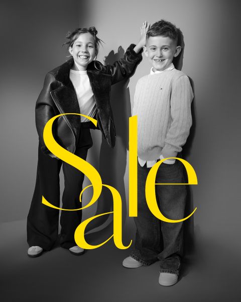 Due bambini sorridenti posano in abiti eleganti con la parola "Sale" in grandi lettere gialle sopra l'immagine.