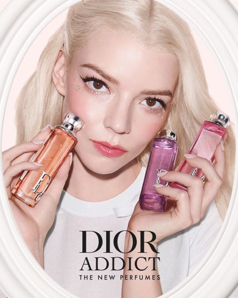 Una donna con i capelli biondi tiene in mano tre flaconi di profumo Dior Addict nei toni dell'arancione, del rosa e del viola, con il testo "DIOR ADDICT THE NEW PERFUMES".