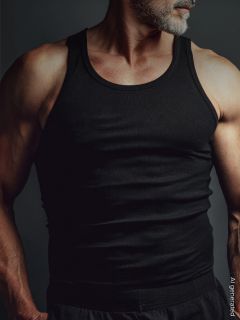 Un uomo muscoloso con la barba grigia indossa una canottiera nera e si trova di fronte a uno sfondo scuro. Il suo viso è parzialmente fuori dall'inquadratura.