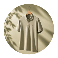 Ein hellolivgrünes Poloshirt auf einem Holzkleiderbügel, mit sanften Schatten und einem schlichten beigen Hintergrund.