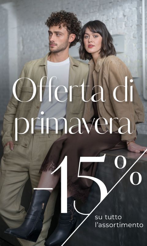 Un uomo e una donna in eleganti outfit primaverili posano in una casa. Il testo recita: "Offerta di primavera -15% su tutto l'assortimento.