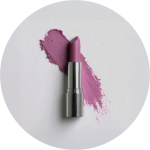 Ein rosafarbener Lippenstift in einer silbernen Hülse liegt auf einer weißen Fläche, hinter der rosa Lippenstift verschmiert ist.