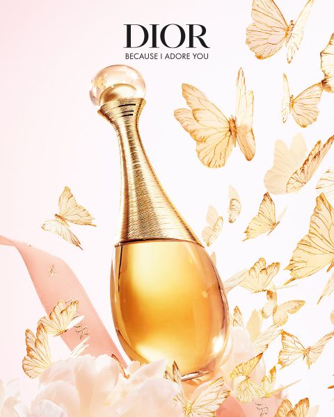 Un flacone di profumo Dior dorato, circondato da farfalle dorate fluttuanti, un fiocco rosa e delicati fiori bianchi con il testo "DIOR Because I Adore You".