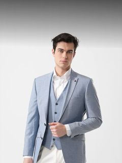 Uomo in abito azzurro con camicia bianca, in piedi davanti a un semplice sfondo bianco, che guarda con sicurezza la fotocamera.