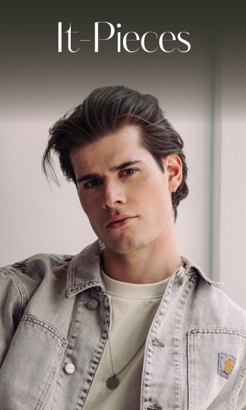Un giovane uomo con capelli curati, che indossa una giacca di jeans chiara e una camicia bianca e guarda la fotocamera sotto il testo "It-Pieces".