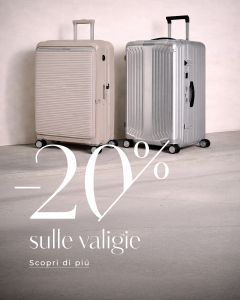 Due grandi valigie, una beige e una argento, sono posizionate in verticale su un pavimento chiaro. Sovrapposizione di testo: "-20% sulle valigie. Scopri di più.".