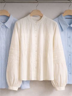 Tre camicie button-down con colletto su appendiabiti, una camicia bianca testurizzata al centro e due camicie azzurre su entrambi i lati.