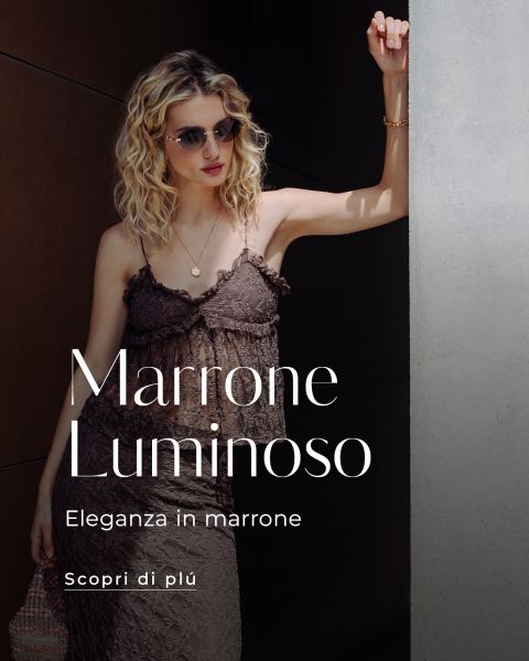 Una donna in un abito di pizzo marrone e con occhiali da sole sta in piedi alla luce del sole. Il testo recita: "Marrone Luminoso, Eleganza in marrone, Scopri di più.