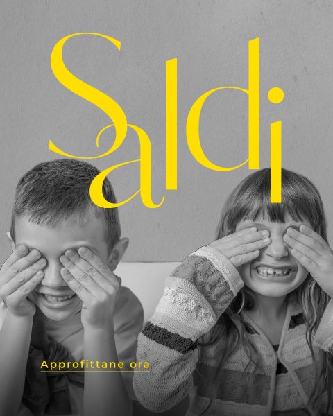 Due bambini sorridenti si coprono gli occhi, sopra di loro c'è scritto in grande carattere giallo "Saldi" e sotto, in carattere giallo più piccolo, "Approfittane ora".