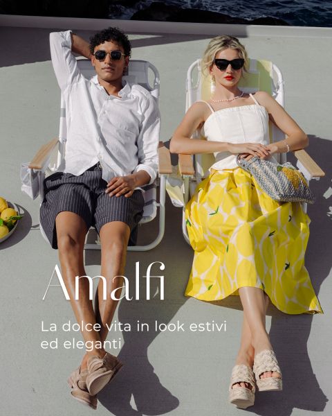 Un uomo e una donna in abbigliamento estivo elegante si rilassano su lettini al sole, nelle vicinanze ci sono limoni. Il testo recita: "Amalfi. La dolce vita in look estivi ed eleganti."
