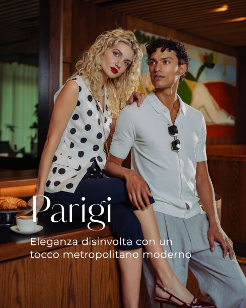 Una donna e un uomo eleganti posano in un caffè chic con pasticcini sul tavolo, incarnando un'eleganza rilassata. Testo italiano sovrapposto all'immagine.