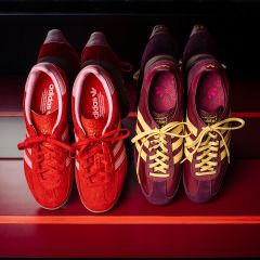 Due paia di sneaker Adidas: un paio rosso con strisce bianche e un paio viola e giallo, entrambi su uno sfondo a strisce rosse, visti dall'alto.