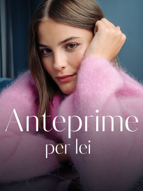 Una donna con un maglione rosa e soffice appoggia la testa sulla mano e guarda in camera. Il testo recita „Anteprime per lei“ in caratteri bianchi.