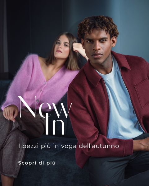 Una donna con un maglione rosa e un uomo con una giacca bordeaux sono seduti su un divano. Il testo recita: "Nuovi arrivi. I capi più trendy dell'autunno. Scopri di più.".
