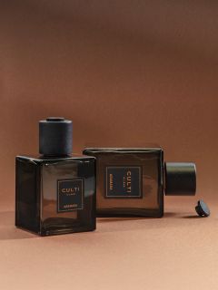 Due flaconi di profumo quadrati in vetro scuro con la scritta „CULTI MILANO ARAMARA“ su sfondo marrone; uno è in piedi, l'altro è sdraiato su un fianco.
