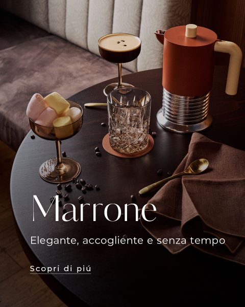 Un tavolo rotondo scuro con caffè, bicchieri, marshmallow in un bicchiere, una moka e chicchi di caffè, accompagnato da un testo in italiano sull'eleganza e l'intramontabilità.