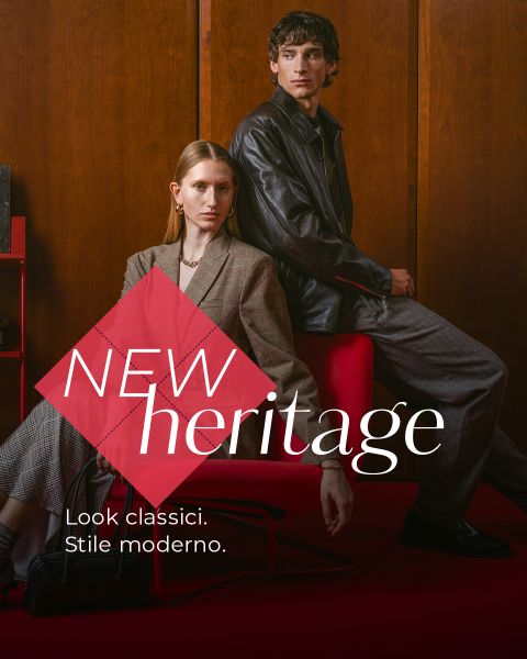 Una donna in blazer e un uomo in giacca di pelle posano in una stanza elegante. Il testo recita: "NEW heritage. Look classici. Stile moderno.".