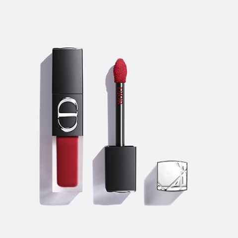 Un rossetto liquido rosso di Dior, con l'applicatore estratto e il tappo argentato accanto, il tutto su sfondo bianco.