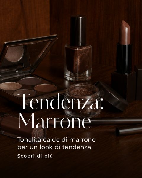 Prodotti per il trucco marroni, tra cui ombretti, smalti, rossetti e pennelli, sono esposti su una superficie di legno scuro. Un testo in italiano promuove le tonalità del marrone.