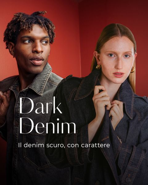 Due modelle in giacche di jeans scuro posano davanti a un muro rosso. Il testo recita: "Dark Denim. Il denim scuro, con carattere.".