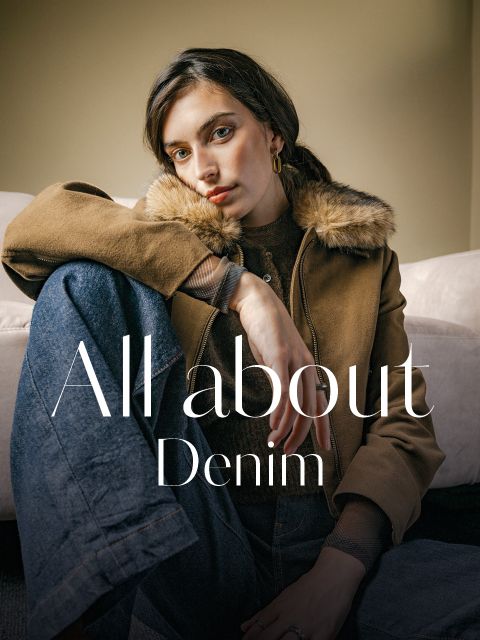 Una donna che indossa una giacca marrone con colletto in pelliccia e jeans, sopra la quale si legge la scritta "All about Denim".