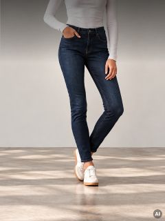 Una persona che indossa una camicia bianca a maniche lunghe, jeans skinny blu scuro e scarpe da ginnastica bianche.