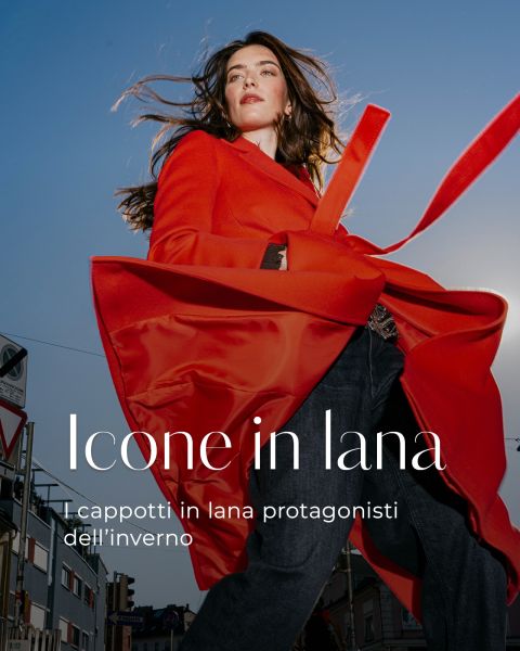 Una persona che indossa un cappotto rosso brillante sotto un cielo azzurro brillante, con il testo italiano "Icone in lana. I cappotti in lana protagonisti dell’inverno."