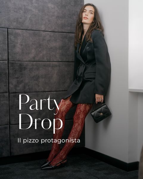 Una donna con un blazer nero e collant di pizzo rosso tiene in mano una piccola borsa nera. Il testo recita: "Party Drop. Il pizzo protagonista".